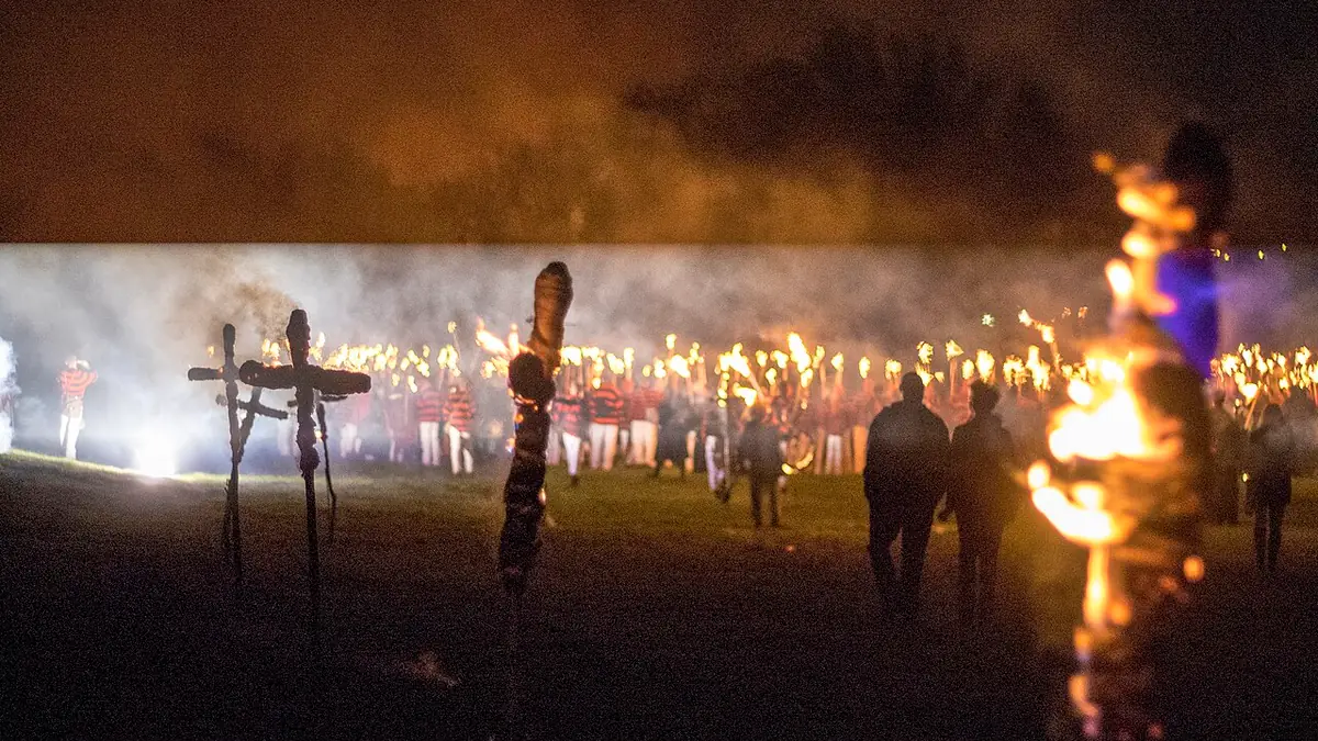 Southover Bonfire Society's fire site at night: torchbearers lined up in the distance, crosses and a burning figure in the foreground